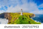 Akraberg Lighthouse, Suduroy Island, Faroe Islands, Denmark. Panoramic view of the rocks, field and the ocean. Lighthouse on top of the mountain. Photography for background, wallpaper, postcards.