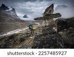 Akshayuk Pass, Baffin Island, Canada. Rear view of hikers looking at dramatic mountain view from summit
