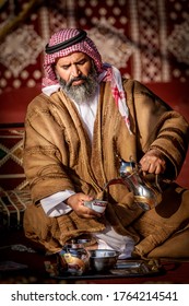 Al Dhafra, United Arab Emirates, December 23, 2015 - An Arab Camel owner serving Arabic coffee to the guest in his tent, He is one of the camel owner exhibiting camel in Al Dhafra camel festival