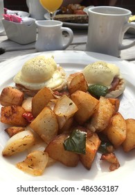 Al Fresco Brunch Of Eggs Benedict And Home Fries Potatoes. Two Poached Eggs, Potatoes And Coffee On White Dinnerware For An Outdoor Sunday Brunch In Brooklyn.