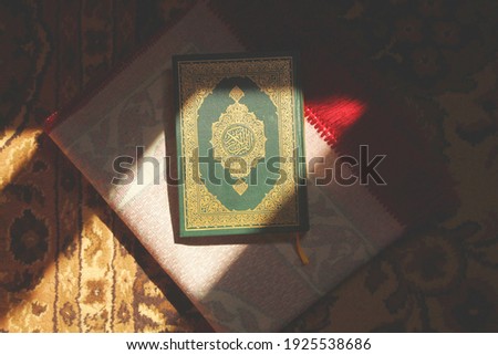 Al Quran Al Karim book with a praying carpet background. wrote on it 