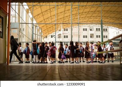 Al Qusais, Dubai, UAE - November 17, 2018: A Teacher And Her Kindergarten Students Holding Their Lunch Bags Falling Up In Line Inside The School Campus Under The Shade After Recess.