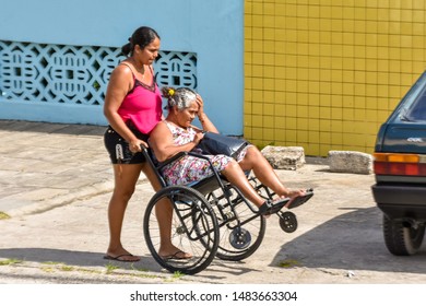 MACEIÓ, ALAGOAS / BRAZIL - AUGUST 19, 2019: Woman Pushing Wheelchair With Difficulty Due To Poor Conservation Of Sidewalks And Neglect Of Local Public Authorities.