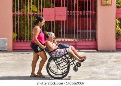 MACEIÓ, ALAGOAS / BRAZIL - AUGUST 19, 2019: Woman Pushing Wheelchair With Difficulty Due To Poor Conservation Of Sidewalks And Neglect Of Local Public Authorities.