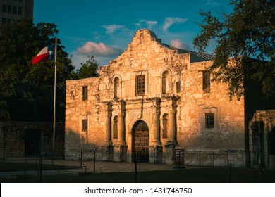 The Alamo At Sunrise With The Texas Flag. Golden Light On The Alamo In San Antonio, Texas In The Morning. Historical Landmark.