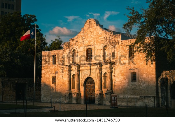 The Alamo at sunrise with the Texas Flag.\
Golden Light on The Alamo in San Antonio, Texas in the morning.\
Historical landmark.