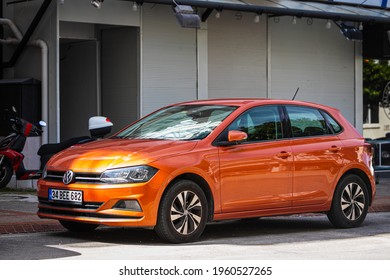 Alanya, Turkey – April 12 2021:  orange Volkswagen Polo    is parked  on the street on a warm summer day against the backdrop of a  street, front  side