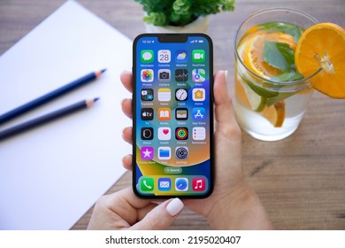 Alanya, Turkey - July 28, 2022: Woman Hand Holding IPhone 13 With Home Screen IOS 16 On The Screen.