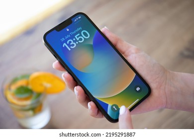 Alanya, Turkey - July 28, 2022: Woman Hand Holding IPhone 13 With Home Screen IOS 16 On The Screen.
