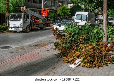 Alanya, Turkey - October 23, 2020: A Pile Of Cut Branches With Dry Leaves On The Background Of An Autotower On A City Street In Alanya. Urban Tree Pruning Service. Caring For Plant