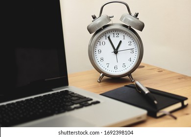 alarm clock alongside laptop and notebook in a workspace, time management concept, work from home - Shutterstock ID 1692398104