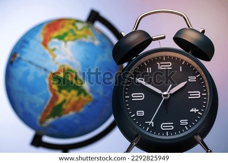 Alarm clock with bells in front of a world globe in a conceptual image of international travel, business, schedules and agenda