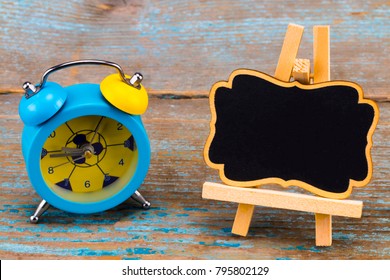  alarm clock and a blackboard with empty space for a text on wooden background.