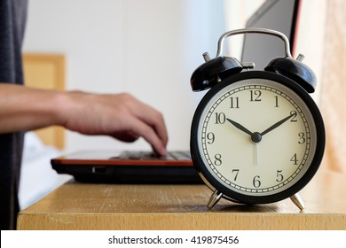 Alarm Clock With Blurred Background Of Businessman Work Overtime Until Morning