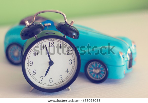 Alarm clock\
and blurred toy car - travel\
concept