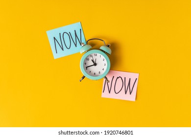  Alarm clock and a colored sticker with the inscription NOW on a yellow background