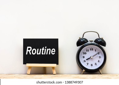 Alarm clock and daily routine words blackboard on desk white background.   Chalkboard write routine text on table for copy space. 