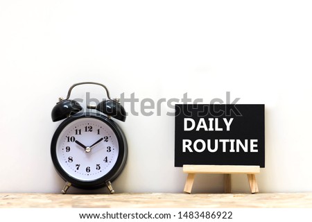 Alarm clock and daily routine words blackboard on desk white background.   Chalkboard write routine text on table for copy space. 