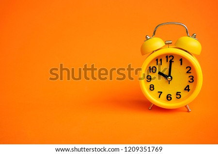 Alarm clock isolated on orange background with copy space