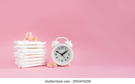 Alarm clock and menstrual sanitary pads. Сoncept of woman critical days and menstruation. Female daily hygiene. Copy space