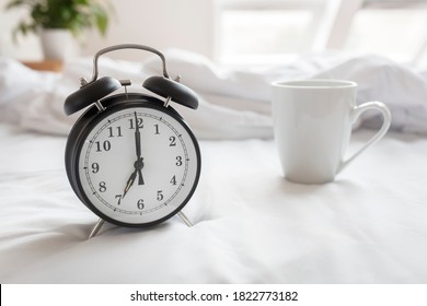 Alarm clock morning wake-up time on bed with coffee cup - Powered by Shutterstock