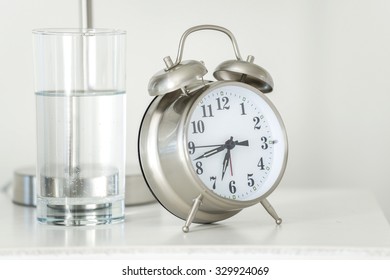 Alarm Clock Next To Glass Of Water