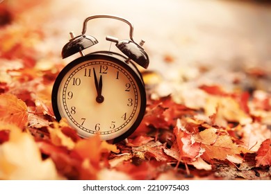 alarm clock on autumn leaves natural background - Shutterstock ID 2210975403