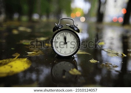 alarm clock on autumn leaves natural background