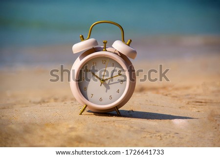 Alarm clock on the beach and sea background.