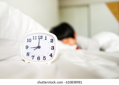 Alarm Clock On Bed And Asian Child Sleeping In Background