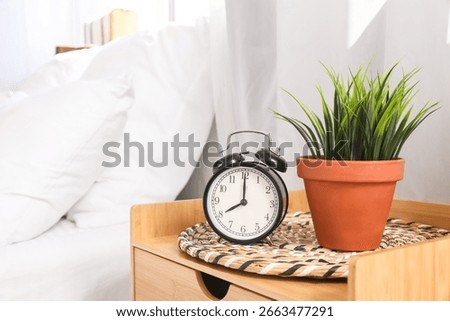 Alarm clock on bedside table in interior of bedroom, closeup