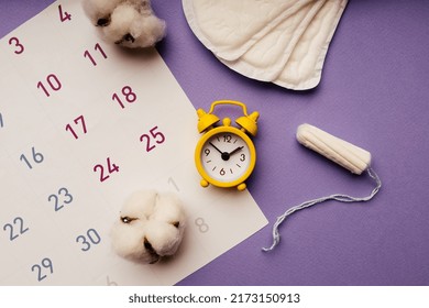 Alarm Clock On Calendar With Menstrual Sanitary Pads And Tampon. Women Menstrual Cycle Concept