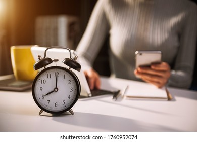 Alarm clock on the desk. Business working in modern office building or home at night using laptop.
 - Powered by Shutterstock