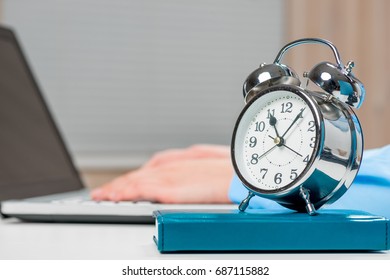 Alarm clock on desk in office close-up and secretary's hands out of focus - Shutterstock ID 687115882