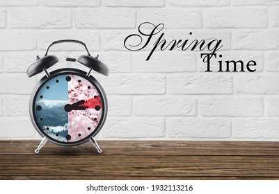 Alarm Clock On Table Against White Brick Background With Text SPRING TIME. Concept Of Time Change