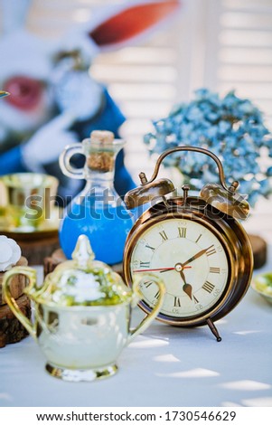 alarm clock on a table decorated under Alice in Wonderland