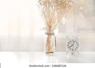Alarm clock on the table in a white room with light orange. - Powered by Shutterstock