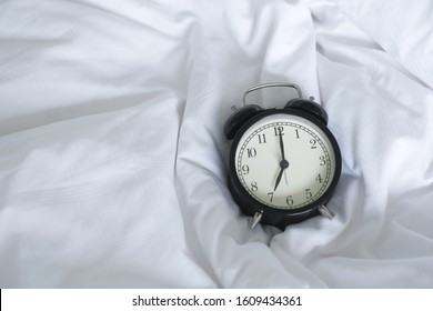 Alarm Clock On White Bed  