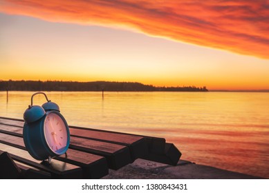 Alarm clock on a wooden bench on the shores of Lake Constance, at sunrise, in Konstanz, Germany. Early morning. Wake up concept. Start of the day.