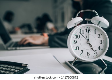 Alarm clock on wooden table with business discussion people group or meeting team background,Time concept at early morning or overtime in evening - Shutterstock ID 1417800872