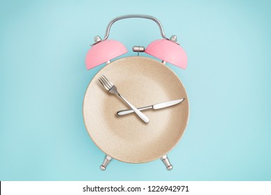 Alarm clock and plate with cutlery . Concept of intermittent fasting, lunchtime, diet and weight loss - Shutterstock ID 1226942971
