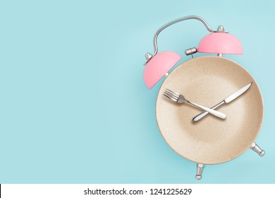 Alarm clock and plate with cutlery . Concept of intermittent fasting, lunchtime, diet and weight loss - Shutterstock ID 1241225629