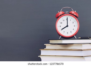 alarm clock red,pen on book, stationery chalk blackboard background. Alarm clock preparation for note and reading book. Education back to school concept. Leave empty copy space for text. - Powered by Shutterstock