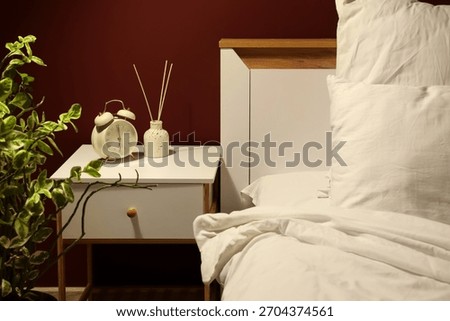 Alarm clock with reed diffuser on nightstand in dark bedroom