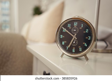 Alarm Clock Set For An Early Morning Wake Up Call At Seven Standing On A Bedside Table