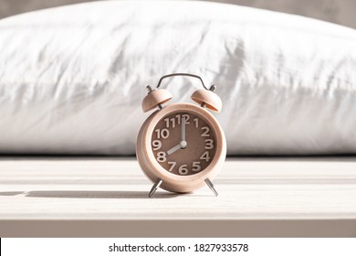 Alarm Clock Stands On Pillow In Morning Sunlight, Morning Wake Up Time, Sleep Time, Healthy Sleep. High Quality Photo