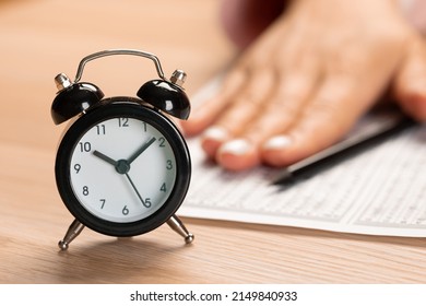 Alarm Clock For A Student Writing Exams, Taking An Exam Room With A Pencil Holding On An Optical Form Of A Standardized Test With Answers