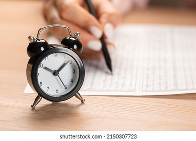 Alarm Clock For A Student Writing Exams, Taking An Exam Room With A Pencil Holding On An Optical Form Of A Standardized Test With Answers