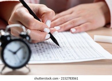 Alarm Clock For A Student Writing Exams, Taking An Exam Room With A Pencil Holding On An Optical Form Of A Standardized Test With Answers