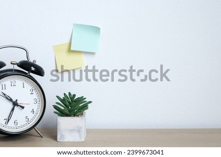 Alarm clock, succulent and sticky notes on wooden table with empty space